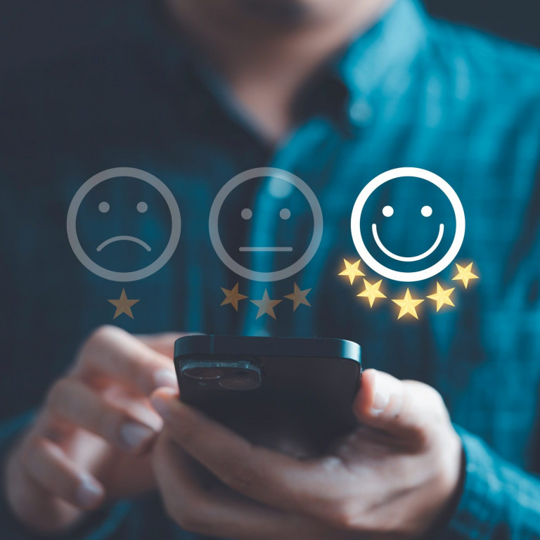 Businessman using smartphone to give five glowing golden stars and smile face icon for excellent evaluation survey after client use product and service from customer satisfaction concept.